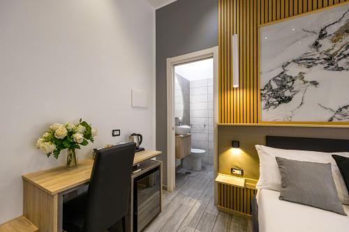 a bedroom with a desk and a bed with a vase of flowers at Hotel Bella Napoli in Naples