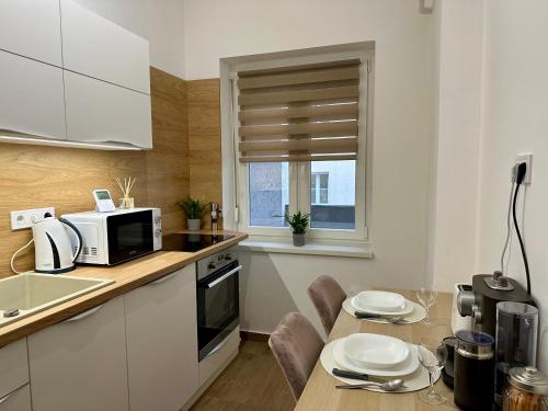 eine Küche mit einem Tisch und einer Mikrowelle in der Unterkunft Mate Gold Apartment in Szeged