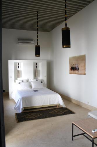 a bedroom with a white bed and two pendant lights at Riad Yamcha in Meknès