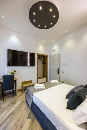 a bedroom with a bed and a desk and a tv at Hotel Bella Napoli in Naples
