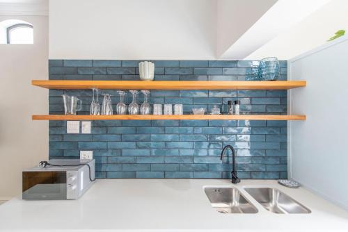 uma cozinha com uma parede de tijolos azuis com prateleiras de madeira em Franschhoek Colours em Franschhoek