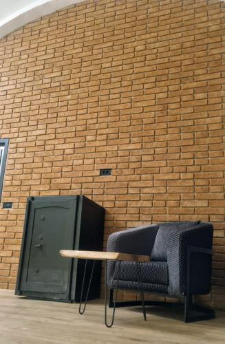 a table and a chair in front of a brick wall at TRESOR Delux Apartment in Osijek