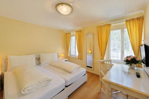 a bedroom with a bed and a table and a desk at Seehof Hotel Du Lac in Weggis