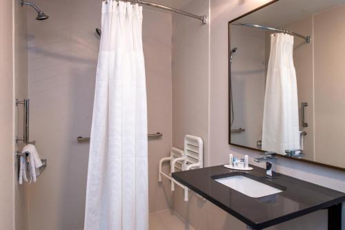 a bathroom with a white shower curtain and a sink at Fairfield Inn & Suites Greensboro Wendover in Greensboro
