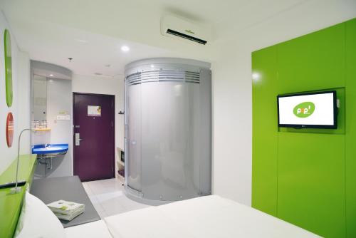 una camera ospedaliera con una camera verde e bianca con doccia di POP! Hotel Kemang Jakarta a Giacarta