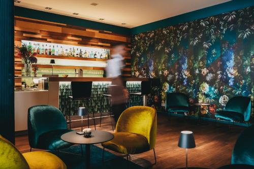 a man walking past a bar with a painting on the wall at Boutique Hotel Atrium München in Munich