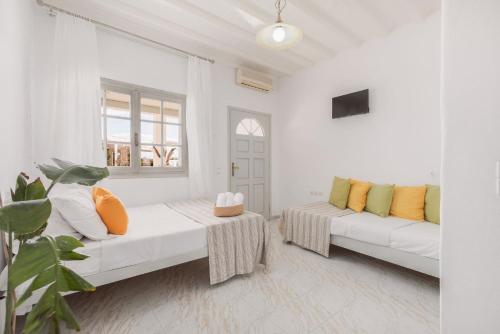 a white room with two beds and a window at Dibellee Mykonos Studios in Glastros