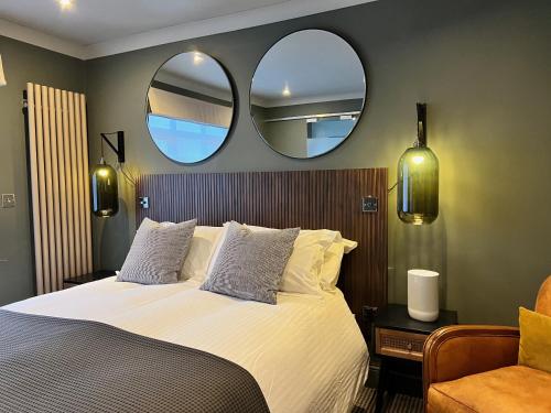 a bedroom with a bed with two mirrors on the wall at Rockmount Rooms & Apartment in Tavistock