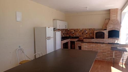 a kitchen with a white refrigerator and a brick fireplace at Chácara nossa senhora Aparecida in Suzano