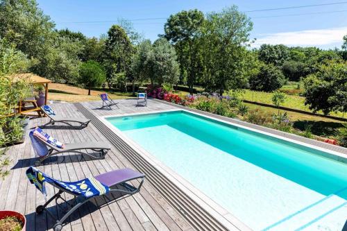 - une piscine sur une terrasse en bois avec 2 chaises à côté dans l'établissement Villa KalonBreizh, Piscine privée chauffée & Sauna, à Plouhinec