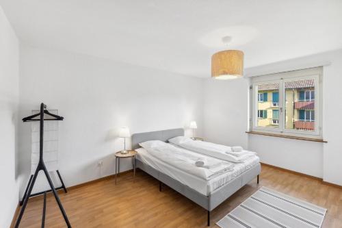 a white bedroom with a bed and a window at Charming Apartments, Just 27 Minutes to Zurich Center in Zürich