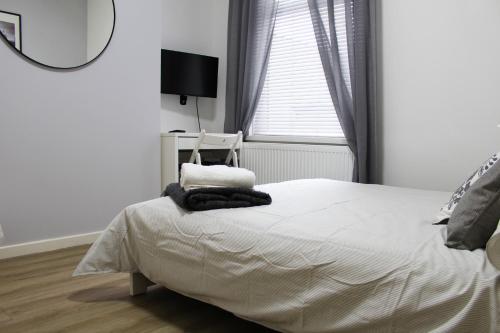 Modern ground floor flat - 15 min to Central London في لندن: غرفة نوم بيضاء مع سرير ومرآة