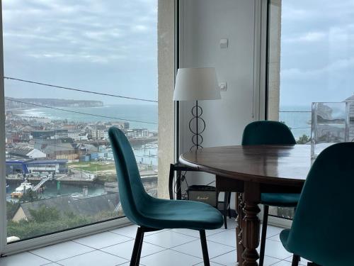 une table et des chaises dans une pièce avec une grande fenêtre dans l'établissement Maison vue mer, port et ville, à Fécamp