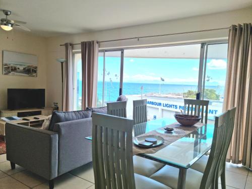 a living room with a dining room table with a view of the ocean at '11 Gordonia'- 2 En-suite Bedrooms, Beach access & Great location in Cape Town