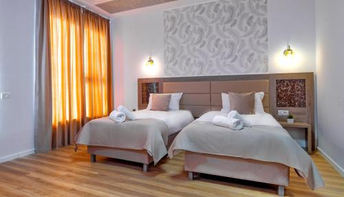 a bedroom with two beds with white sheets at SIR FUNDENI HOTEL in Bucharest