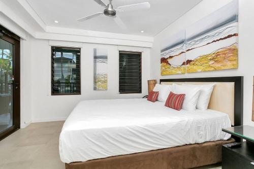 a bedroom with a large bed with white walls at Poolside Bliss: A Modern Resort Sanctuary in Port Douglas