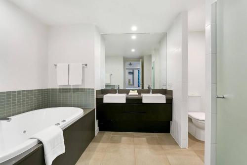 a bathroom with a tub and a sink and a toilet at Poolside Bliss: A Modern Resort Sanctuary in Port Douglas