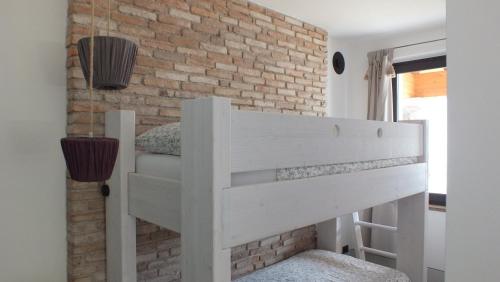 a white bunk bed in a room with a brick wall at Rocca d'Anfo B&B-Apartments Lake View in Rocca dʼAnfo