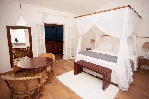 sypialnia z łóżkiem z baldachimem oraz stołem i krzesłami w obiekcie Saint Tropez Praia Hotel w mieście Arraial d'Ajuda