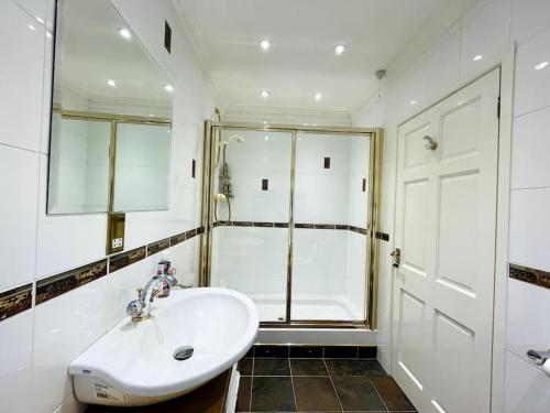 a white bathroom with a shower and a sink at Karinya suite in Llanvaches