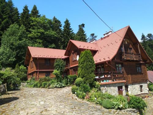 uma grande casa de madeira com um telhado vermelho em Dom Gościnny Dudek em Krynica Zdrój