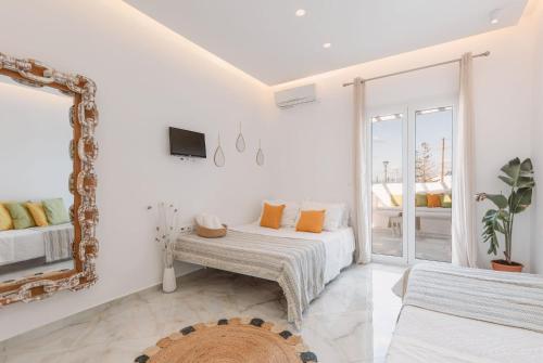 Habitación blanca con cama y espejo en Dibellee Mykonos boutique studios, en Glastros