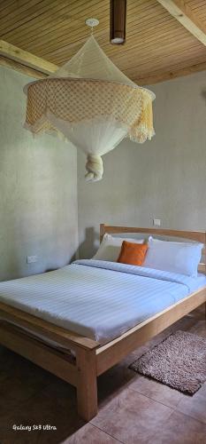 a bed with a chandelier hanging from the ceiling at Tusubira village in Jinja