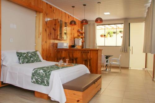 a bedroom with a bed and a table and a kitchen at Studio Aconchego Correntina in Correntina