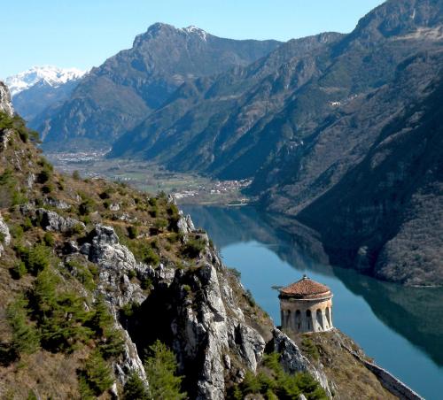 a building on the edge of a mountain overlooking a lake at Rocca d'Anfo B&B-Apartments Lake View in Rocca dʼAnfo