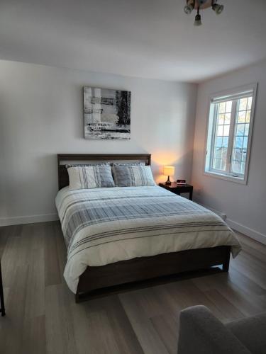 a white bedroom with a large bed and a window at Gîte B&B - Aubergélit inc in Saint-Jean-Port-Joli