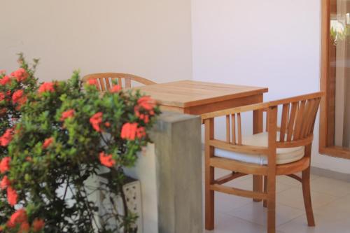 a wooden table and chair next to a plant with red flowers at Villa Seruni Lovina in Lovina