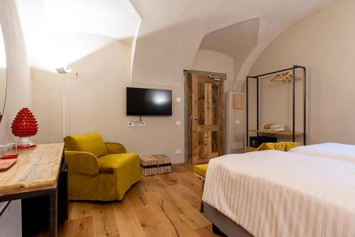 a bedroom with a bed and a chair and a tv at Relais Villa Carrara in Villa di Serio