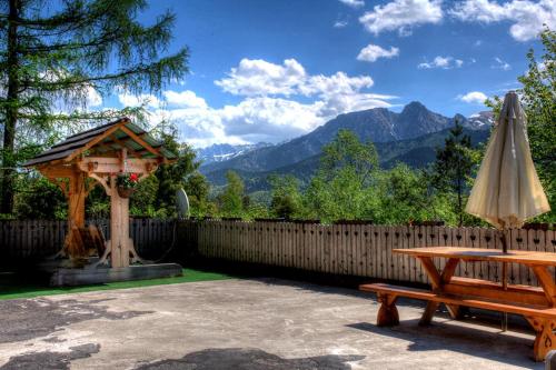 a wooden bench and an umbrella and a table at Willa Pod Orłem Jacuzzi Sauna in Kościelisko