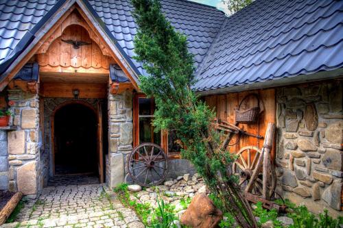 a wooden house with a tree in front of it at Willa Pod Orłem Jacuzzi Sauna in Kościelisko