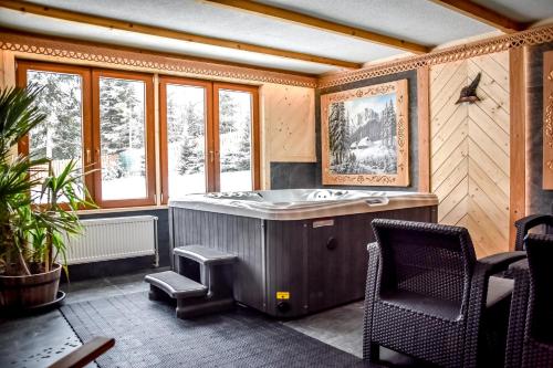 a bathroom with a tub and a chair and windows at Willa Pod Orłem Jacuzzi Sauna in Kościelisko