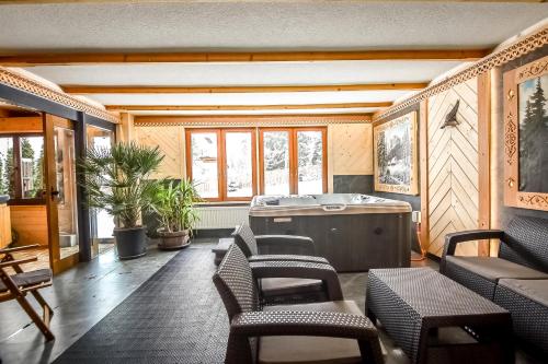 a room with a hot tub and chairs and windows at Willa Pod Orłem Jacuzzi Sauna in Kościelisko