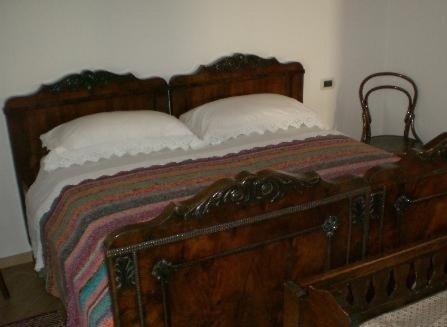 a bedroom with a wooden bed with two pillows at Agriturismo Le Cavade in Cembra