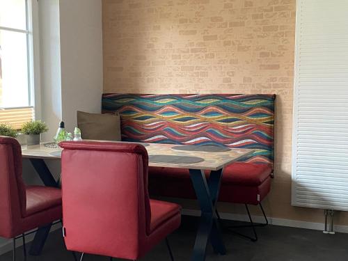 a table with red chairs and a colorful blanket on a wall at Haus Mariechen Whg 2 in der Nähe zum Silbersee mit gemütlicher Terrasse & Sauna in Frielendorf