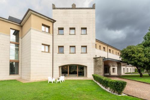 - un grand bâtiment blanc avec deux chaises dans la cour dans l'établissement Parador de Villafranca del Bierzo, à Villafranca del Bierzo