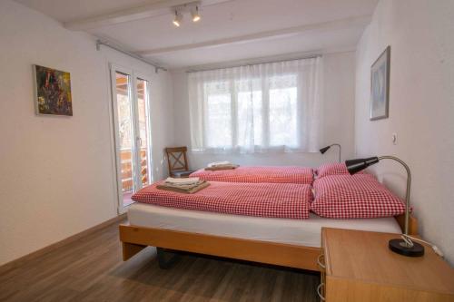 Schlafzimmer mit einem Bett mit roten und weißen Kissen in der Unterkunft Chalet Azeno EG in Adelboden