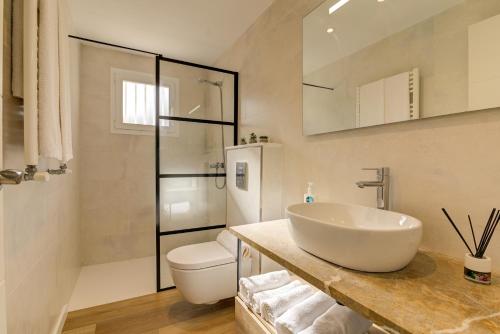 a white bathroom with a sink and a toilet at Orquidia by Rentallorca - Private pool and Garden in Port d'Alcudia