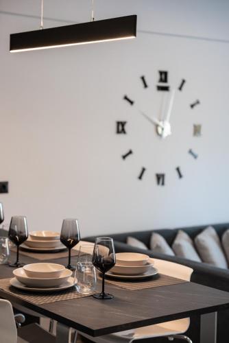 a table with chairs and a clock on a wall at Valentinos Apartments in Kallithea Halkidikis