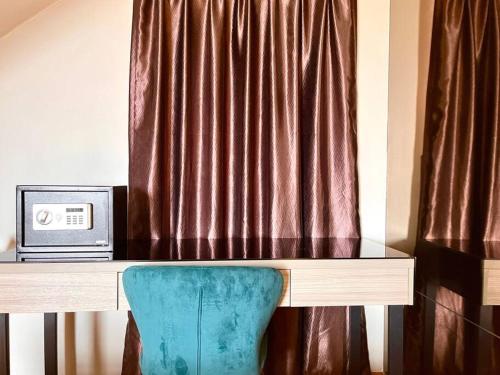 a desk with a computer and a chair in front of a curtain at HillLand Suites in Ayer Keroh