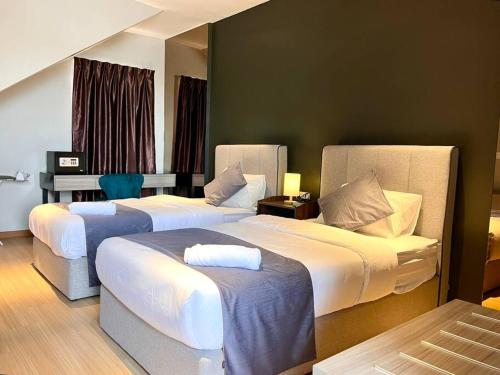 a hotel room with two beds and a table at HillLand Suites in Ayer Keroh