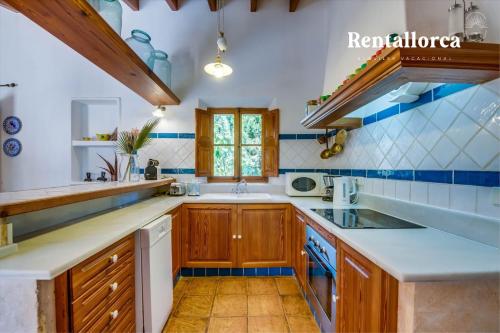 a kitchen with wooden cabinets and blue and white tiles at Finca Son Guillotet by Rentallorca in Maria de la Salut