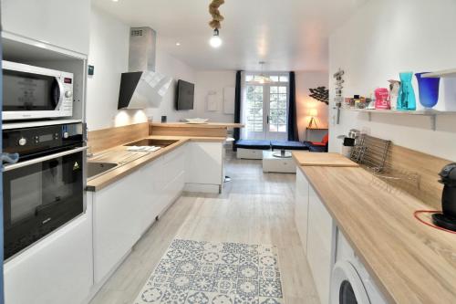 une cuisine avec des armoires blanches et un comptoir dans l'établissement L'Escale Cancalaise - Maison de pêcheur 150m du port, à Cancale