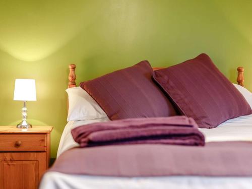 1 cama con almohadas moradas y pared verde en 1 Bed in Liskeard 85888 en Saint Neot