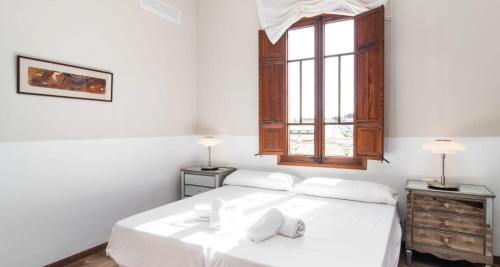 Can Bombarda by Rentallorca في يوبي: غرفة نوم بيضاء مع سرير مع ملاءات بيضاء ونافذة