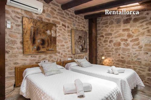 two beds in a room with stone walls at Finca Comteses Petit by Rentallorca in Alcudia