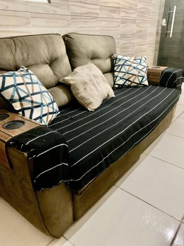 Sofá marrón con almohadas en el suelo en Quarto privativo Caruaru fácil acesso para o pátio de eventos e feira da sulanca en Caruaru